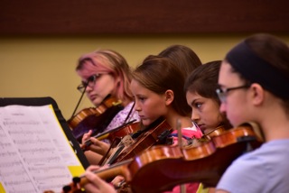 Young Musicians practice the violin as a group