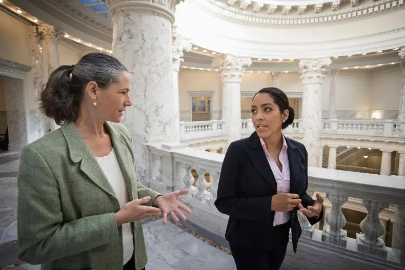 Women with map jobs walk the the halls of a government building