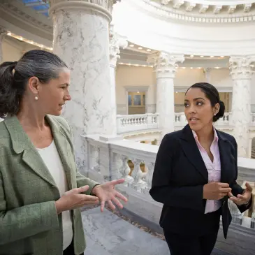 Women with map jobs walk the the halls of a government building