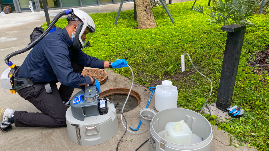 Walter Lamar, executive director of Facilities, Safety and Compliance for the Miller School of Medicine setting up an autosampler device to collect wastewater outside the Lakeside Village residential hall.