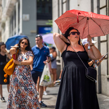 A woman holds an umbrella to shelter from the sun during a hot sunny day in Madrid, Spain, Monday, July 18, 2022. (AP Photo/Manu Fernandez)