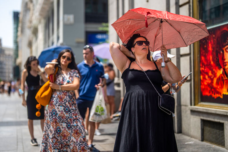 A woman holds an umbrella to shelter from the sun during a hot sunny day in Madrid, Spain, Monday, July 18, 2022. (AP Photo/Manu Fernandez)