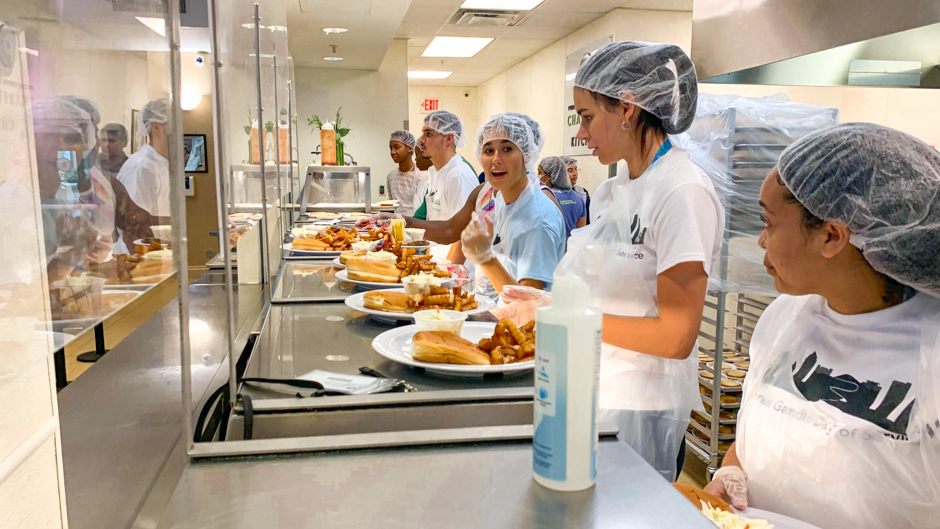 Students volunteering at Camillus House, a nonprofit that provides meals and housing to the Miami-Dade County community, prepared hot food for distribution.