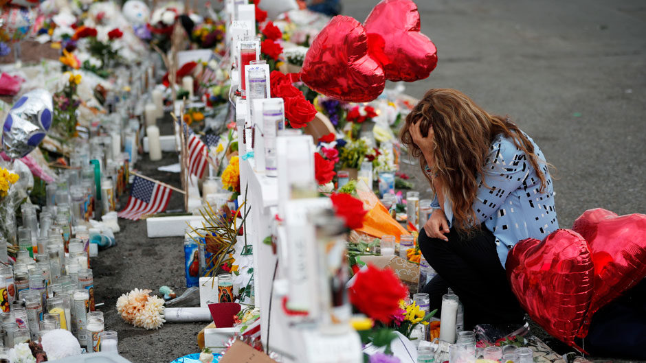 Gloria Garces kneels in front of crosses at a makeshift memorial near the scene of a mass shooting at a shopping complex Tuesday, Aug. 6, 2019, in El Paso, Texas. (AP Photo/John Locher)