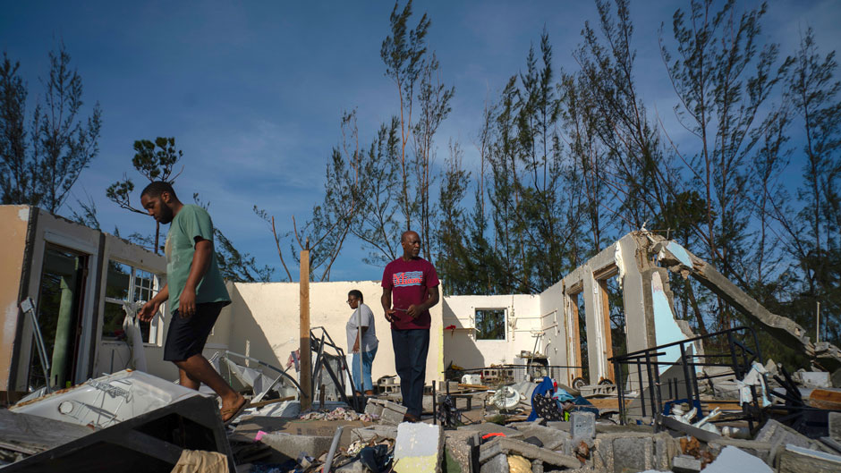 George Bolter, left, and his parents walk through the remains of his home destroyed by Hurricane Dorian in the Pine Bay neighborhood of Freeport, Bahamas, Wednesday, Sept. 4, 2019. Rescuers trying to reach drenched and stunned victims in the Bahamas fanned out across a blasted landscape of smashed and flooded homes Wednesday, while disaster relief organizations rushed to bring in food and medicine. (AP Photo/Ramon Espinosa)
