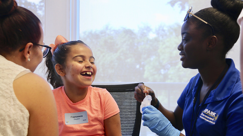 Nichelle Decius, a member of the UM-NSU CARD research staff, takes a saliva sample from a girl who is enrolling in the SPARK study.