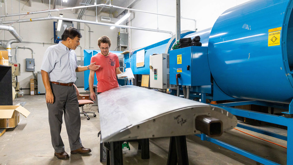 Professor GeCheng Zha and College of Engineering graduate student Brendan McBreen examine a prototype wing containing micro-compressors that would generate vertical lift and propulsion in an electric V/STOL aircraft.