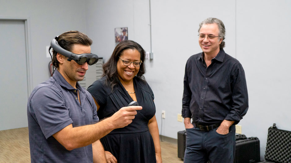 The Center for Computational Science's Michael Mannino demonstrates Magic Leap's headset for the Frost School's Valerie Coleman and Jeffrey Marc Buchman.