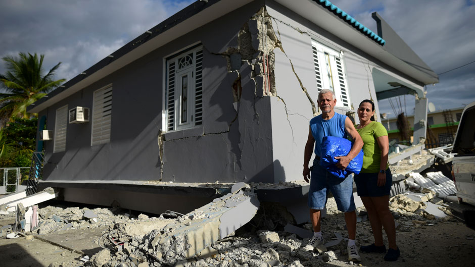 67 year-old William Mercuchi, center, and his daughter Joan pose for photos in front of their house that collapsed after the previous day's magnitude 6.4 earthquake in Yauco, Puerto Rico, Wednesday, Jan. 8, 2020. More than 250,000 Puerto Ricans remained without water on Wednesday and another half a million without power, which also affected telecommunications. (AP Photo/Carlos Giusti)