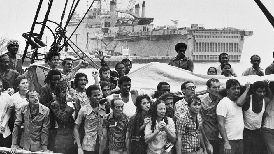 In this May 1980 file photo, refugees from Cuba stand on the deck of their boat as they arrive at a rainy Key West, Fla. In the Mariel Boatlift, more than 100,000 Cubans fled the island by sea in the space of just six months. (AP Photo/Eddie Adams)