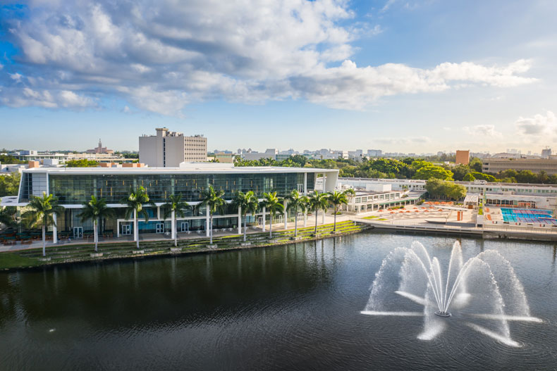 An aerial view of the Shalala Student Center on Lake Osceola and Cobb Fountain, with the City of Coral Gables in the distance.