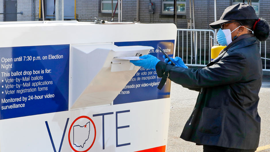 Marcia McCoy drops her ballot into a box outside the Cuyahoga County Board of Elections, Tuesday, April 28, 2020, in Cleveland, Ohio. The first major test of an almost completely vote-by-mail election during a pandemic is unfolding Tuesday in Ohio, offering lessons to other states about how to conduct one of the most basic acts of democracy amid a health crisis. (AP Photo/Tony Dejak)
