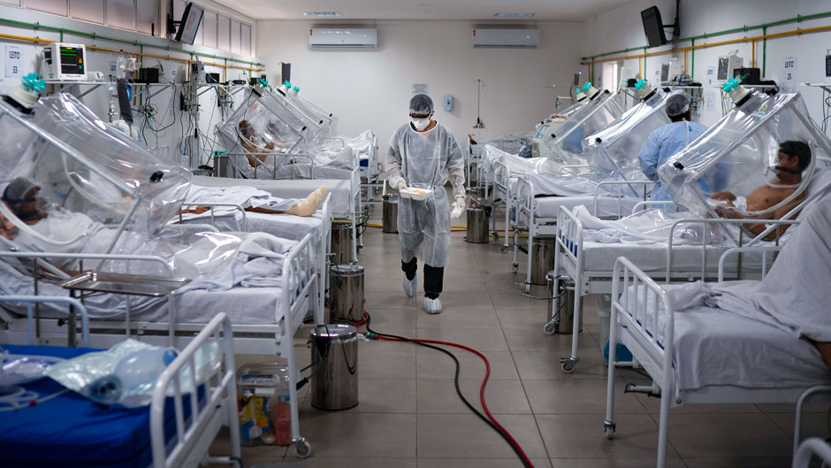 COVID-19 patients are treated inside a non-invasive ventilation system named the 'Vanessa Capsule' at the municipal field hospital Gilberto Novaes in Manaus, Brazil, Monday, May 18, 2020. The field hospital set up inside a school currently has nearly 150 beds and is operating near its limit as it treats patients both from the capital and from rural areas of the Amazon state. (AP Photo/Felipe Dana)