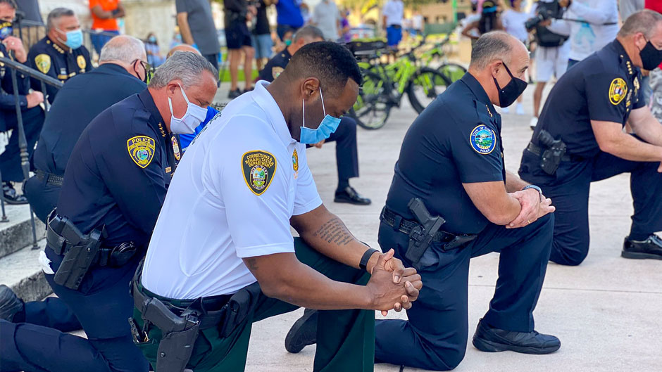 Police officers kneel during a protest in Coral Gables on Saturday, May 30, 2020. Photo courtesy Roy Ramos/WPLG