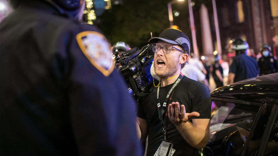 Associated Press videojournalist Robert Bumsted reminds a police officer that the press are considered "essential workers" and are allowed to be on the streets despite a curfew, Tuesday, June 2, 2020, in New York. New York City police officers surrounded, shoved and yelled expletives at two Associated Press journalists covering protests in the latest aggression against members of the media during a week of unrest around the country. Portions of the incident were captured on video by Bumsted, who was working with photographer Wong Maye-E to document the protests in lower Manhattan over the killing of George Floyd in Minneapolis. (AP Photo/Wong Maye-E)