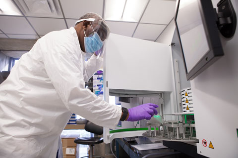 Medical technologist Haider Saleh loads some COVID-19 samples into the a DNA extraction instrument used to detect the U.K. variant, at the Miller School of Medicine.