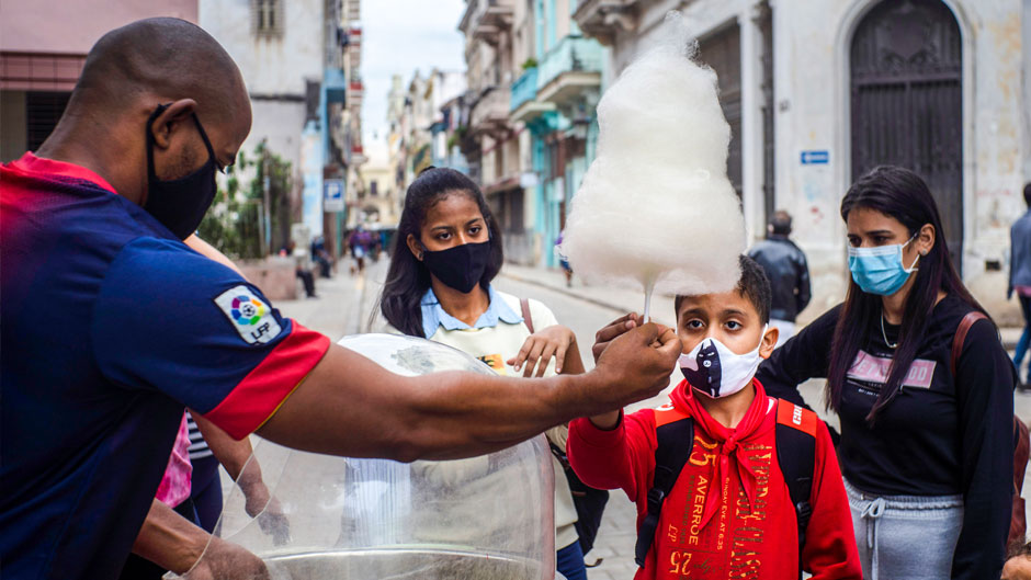 In this Jan. 11, 2021 file photo, people wearing masks as a precaution against the spread of the new coronavirus wait for their turn to buy cotton candy in Havana, Cuba. In 2021, the government is implementing a deep financial reform that reduces subsidies, eliminates a dual currency that was key to the old system, and raises salaries, in hopes of boosting productivity to help alleviate an economic crisis and reconfigure a socialist system that will still grant universal benefits such as free health care and education. (AP Photo/Ramon Espinosa, File)