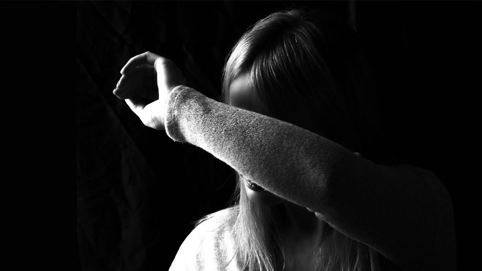 Black and white image of a woman shielding her face with her arm