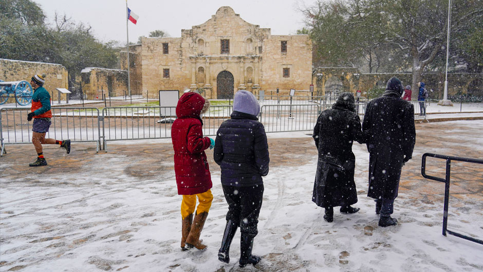 People walk through the snow as they pass the Alamo, Thursday, Feb. 18, 2021, in San Antonio. Snow, ice and sub-freezing weather continue to wreak havoc on the state's power grid and utilities. (AP Photo/Eric Gay)