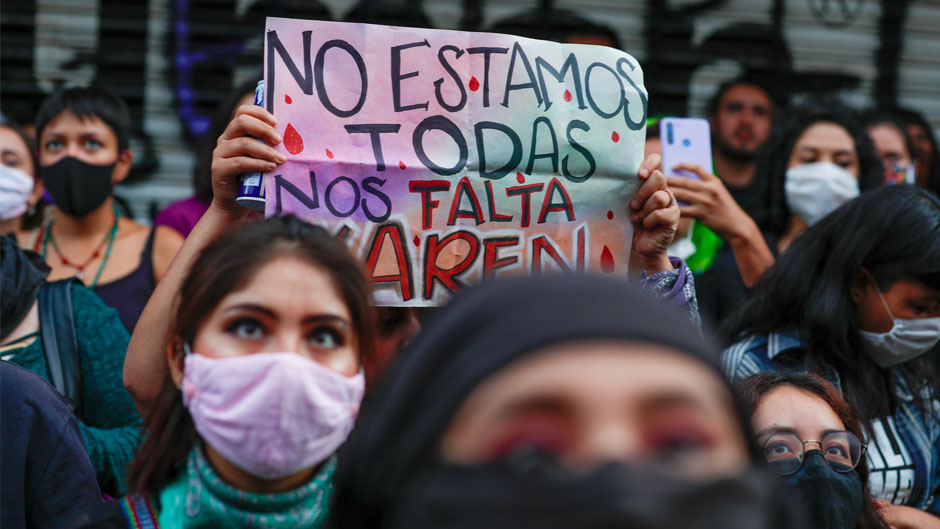 A young woman holds up a sign reading in Spanish, "We aren't all here, Karen is missing," as feminists and crime victims of violence who have been occupying the offices of the governmental Human Rights Commission celebrate an "anti-grito," a day ahead of the traditional "Grito de Dolores," Mexico's annual shout of independence, in Mexico City, Monday, Sept. 14, 2020. The activists, who are demanding justice for victims of femicide, sexual assault, forced disappearances, and other violent crimes, say they will turn the offices into a refuge for victims.(AP Photo/Rebecca Blackwell)