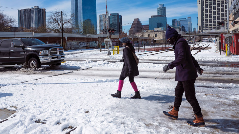 People walk on snowy streets Tuesday, Feb. 16, 2021, in Austin, Texas. Temperatures dropped into the single digits as snow shut down air travel and grocery stores. (AP Photo/Ashley Landis)