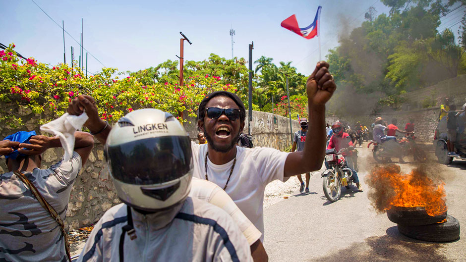 A protester waves a small Haitian flag during a protest to demand the resignation of President Jovenel Moise and against a constitutional referendum scheduled for June 27, in Port-au-Prince, Haiti, Tuesday, May 18, 2021. ( AP Photo / Joseph Odelyn)