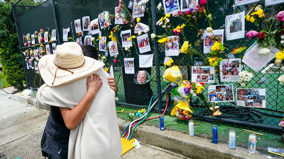 People embrace at a make-shift memorial outside St. Joseph Catholic Church, in Surfside, Fla., Monday, June 28, 2021, near the collapsed building for people still missing or dead. Many people were still unaccounted for after Thursday's fatal collapse. (AP Photo/Gerald Herbert)