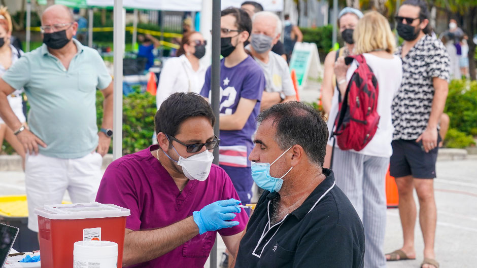 Carlos Anacleto closes his eyes as he receives the Pfizer COVID-19 vaccine from nurse Jorge Tase, as others wait their turn, Wednesday, Aug. 4, 2021, in Miami Beach, Fla. On Tuesday, the CDC added more than 50,000 new COVID-19 cases in the state over the previous three days, pushing the seven-day average to one the highest counts since the pandemic began, an eightfold increase since July 4. (AP Photo/Marta Lavandier)