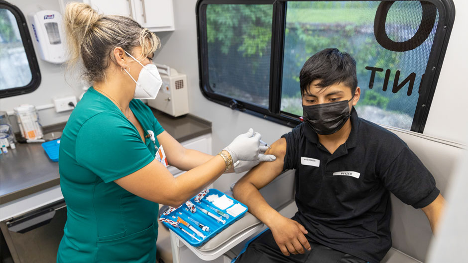 Registered nurse Yelany Lima administers a COVID-19 shot to Jefferson Lopez at a Back to School fair in Homestead last week. The Miller School’s Pediatric Mobile Clinic and Shotz-2-Go vehicles visited the event to offer free school-required vaccines to all children, as well as COVID-19 vaccines to anyone above the age of 12. The Shotz-2-Go vehicle is also offering free COVID-19 testing across the county for children under 18 years old. Photo: Evan Garcia/University of Miami