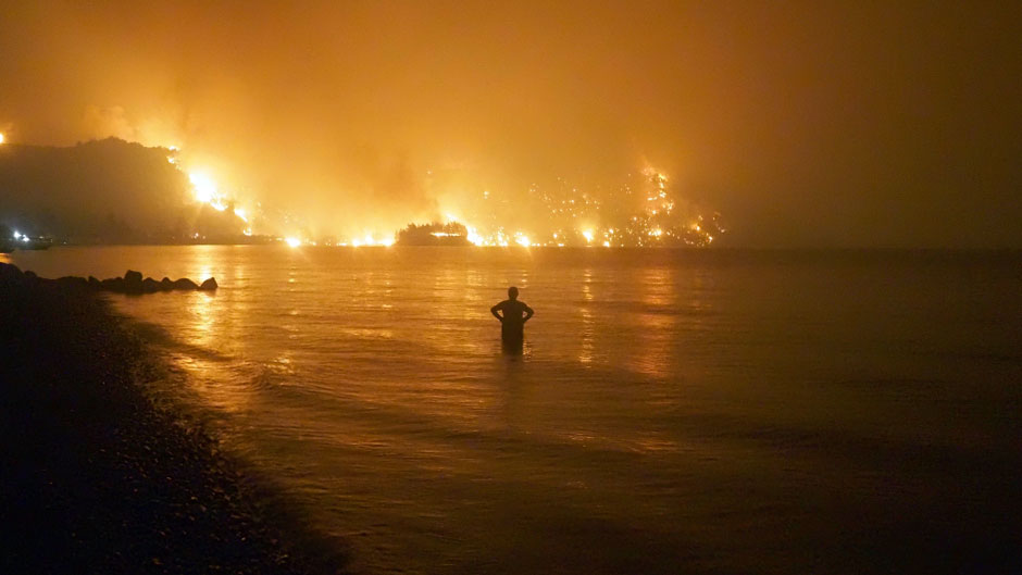 In this file photo dated Friday, Aug. 6, 2021, a man watches as wildfires approach Kochyli beach near Limni village on the island of Evia, about 160 kilometers (100 miles) north of Athens, Greece. Photo: The Associated Press