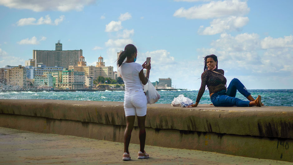 A woman takes a photo of another on the Malecon in Havana, Cuba, Monday, Nov. 8, 2021. Cuba is preparing to reopen to the world on Nov. 15, following COVID-19 lockdown restrictions. (AP Photo/Ramon Espinosa)