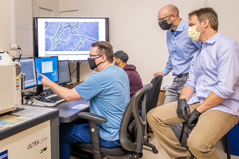 Assistant professors Giacomo Po (seated, right) and James Coakley (standing) and graduate students William Hixson (seated, blue shirt) and Inam Lalani examine an image showing the microstructure of a precipitation-hardened alloy.