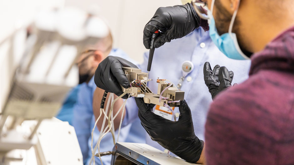 Mechanical and aerospace engineering researchers prepare to mount a nano-indentation device to perform mechanical testing of an alloy. 