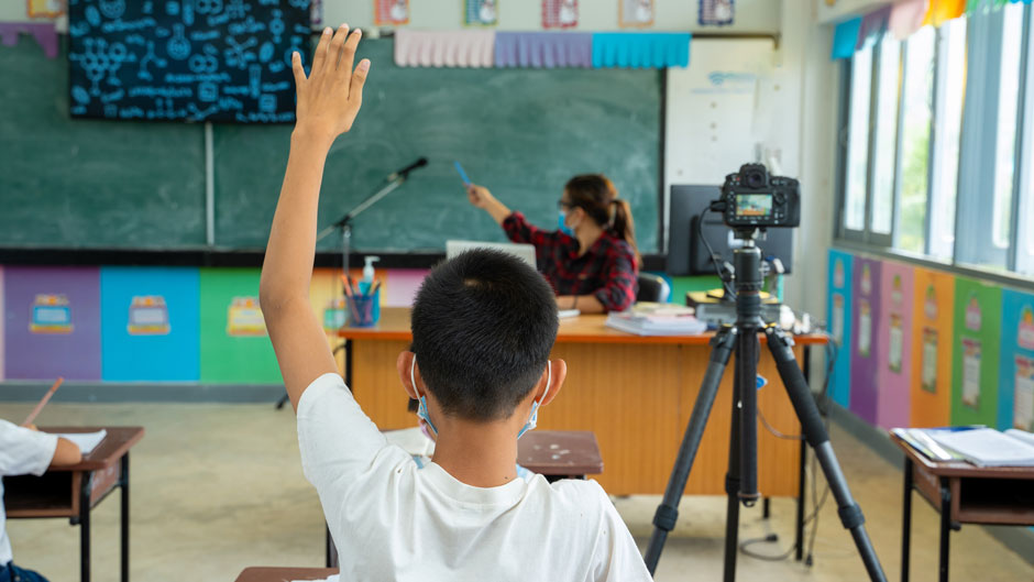 Group of school kids with teacher sitting in classroom online and raising hands. stock photo