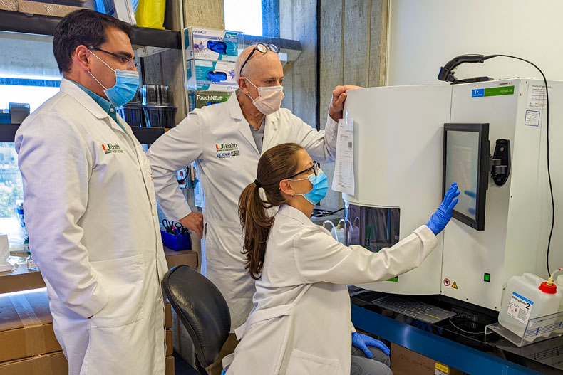 From left, medical technologist Orlando Bracho, Dr. David Andrews, and medical technologist Yamina Carattini use the "Chemagic" machine to purify viral RNA from clinical samples. Photo courtesy Dr. David Andrews.