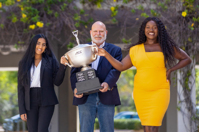 Iman Sami, David Steinberg, and Delphine Djomo pose with the ACC Championship trophy. Photo: Evan Garcia/University of Miami