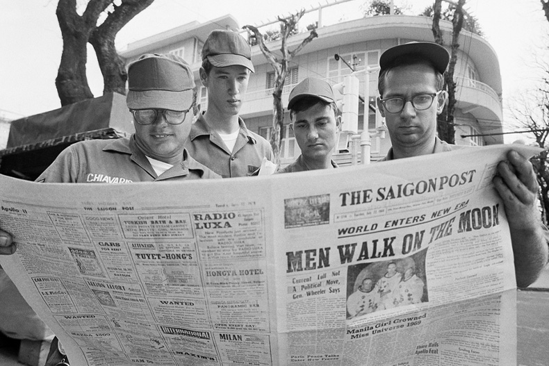 In this July 21, 1969 file photo, U.S. Air Force Sgt. Michael Chivaris, Clinton, Mass.; Army Spec. 4 Andrew Hutchins, Middlebury, Vt.; Air Force Sgt. John Whalin, Indianapolis, Ind.; and Army Spec. 4 Lloyd Newton, Roseburg, Ore., read a newspaper headlining the Apollo 11 moon landing, in downtown Saigon, Vietnam. (AP Photo/Hugh Van Es)