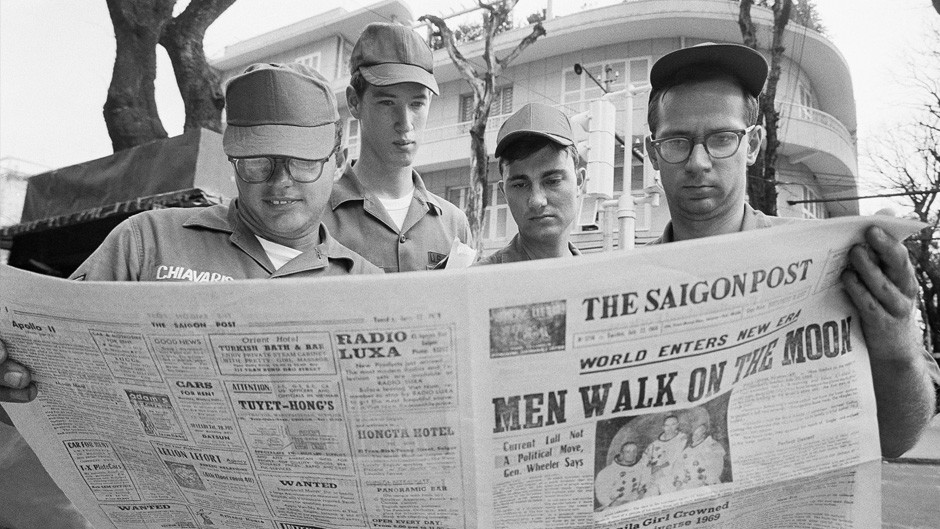 In this July 21, 1969 file photo, U.S. Air Force Sgt. Michael Chivaris, Clinton, Mass.; Army Spec. 4 Andrew Hutchins, Middlebury, Vt.; Air Force Sgt. John Whalin, Indianapolis, Ind.; and Army Spec. 4 Lloyd Newton, Roseburg, Ore., read a newspaper headlining the Apollo 11 moon landing, in downtown Saigon, Vietnam. (AP Photo/Hugh Van Es)