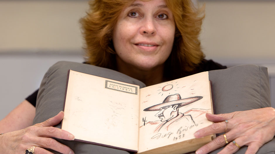 Catherine Steele poses with a book containing a sketch done by Diego Rivera. Photo: Joshua Prezant/University of Miami