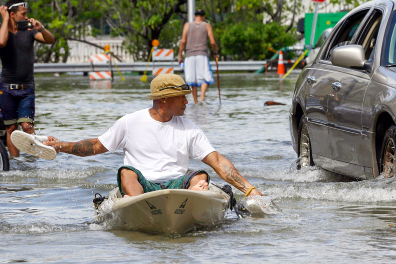 Juan Carlos Sanchez uses his shoes to paddle a kayak on a flooded street near Collins Ave., Wednesday, Sept. 30, 2015, in Miami Beach, Fla. The street flooding was in part caused by high tides due to the lunar cycle, according to the National Weather Service. (AP Photo/Lynne Sladky)