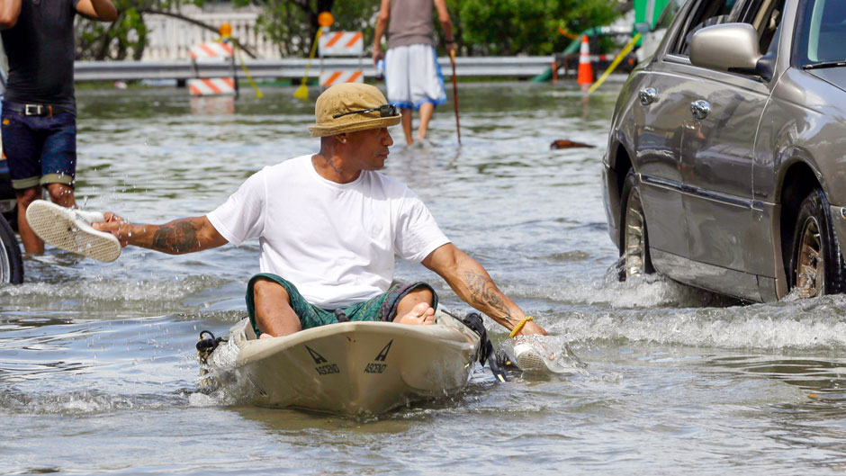 Juan Carlos Sanchez uses his shoes to paddle a kayak on a flooded street near Collins Ave., Wednesday, Sept. 30, 2015, in Miami Beach, Fla. The street flooding was in part caused by high tides due to the lunar cycle, according to the National Weather Service. (AP Photo/Lynne Sladky)