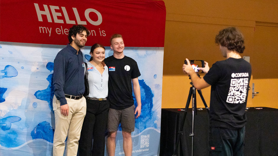 Ethan Rozencwaig, a senior studying ecosystem science and policy; Dale Pantone, a senior studying marine affairs; and Luke Norris, a sophomore studying ecosystem science and policy pose for a photo in front of “HELLO” photographed by Patrick Rodriguez, a Cortada Project intern.