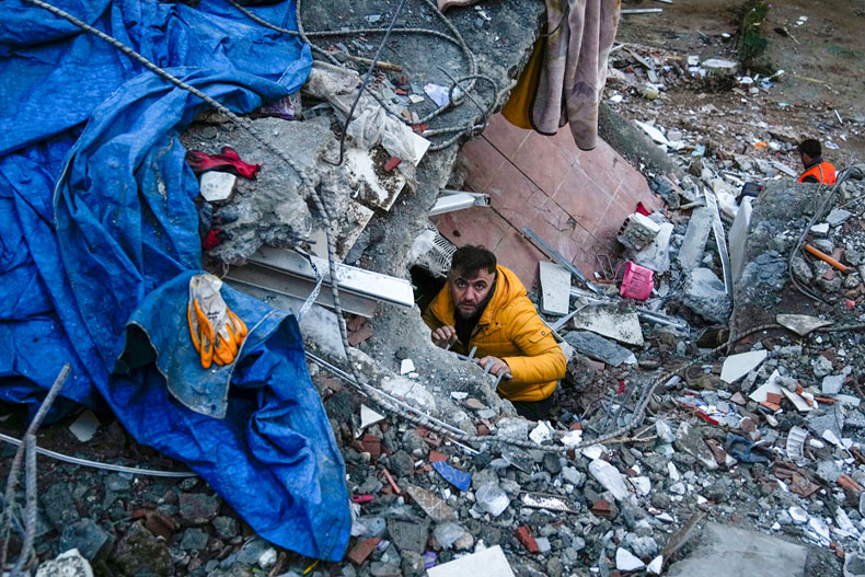 A man searches for people in a destroyed building in Adana, Turkey, Monday, Feb. 6, 2023. A powerful quake has knocked down multiple buildings in southeast Turkey and Syria and many casualties are feared. (AP Photo/Khalil Hamra) 