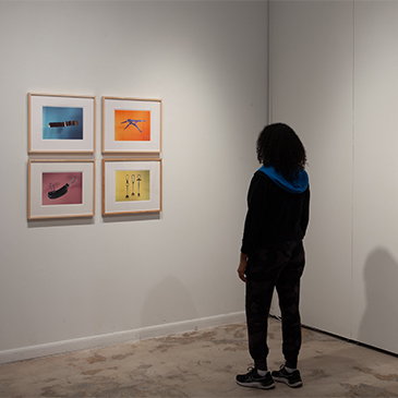 Guest views prints from "The Precipice," an exhibition of photographs from the first monograph by the Miami-based photographer Tony Chirinos, currently on display at the University of Miami gallery located inside the Wynwood Building.  