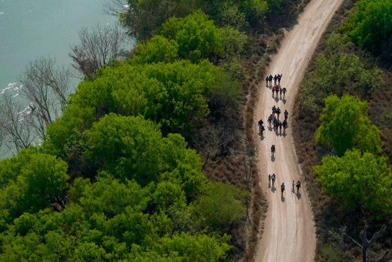 FILE - Migrants walk on a dirt road along the Rio Grande in Mission, Texas, on March 23, 2021, after crossing the U.S.-Mexico border. (AP Photo/Julio Cortez, File)