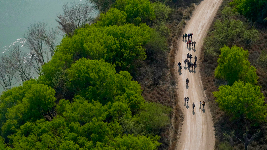 FILE - Migrants walk on a dirt road along the Rio Grande in Mission, Texas, on March 23, 2021, after crossing the U.S.-Mexico border. (AP Photo/Julio Cortez, File)