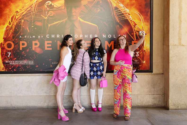 From left, Gabrielle Roitman, Kayla Seffing, Maddy Hiller and Casey Myer take a selfie in front of an "Oppenheimer" movie poster before they attended an advance screening of "Barbie," Thursday, July 20, 2023, at AMC The Grove 14 theaters in Los Angeles. (AP Photo/Chris Pizzello)