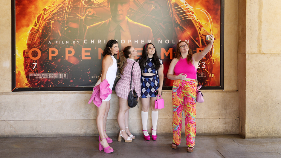 From left, Gabrielle Roitman, Kayla Seffing, Maddy Hiller and Casey Myer take a selfie in front of an "Oppenheimer" movie poster before they attended an advance screening of "Barbie," Thursday, July 20, 2023, at AMC The Grove 14 theaters in Los Angeles. (AP Photo/Chris Pizzello)