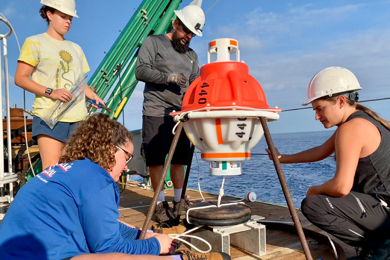 Graduate students Rachel Sampson and Paloma Cartwright and undergraduate oceanography student Allie Cook work with mooring technician Eduardo Jardim to prepare a CPIES monitoring device for deployment. Photo: Courtesy of Lisa Beal