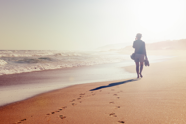 Woman walking on the beach stock photo